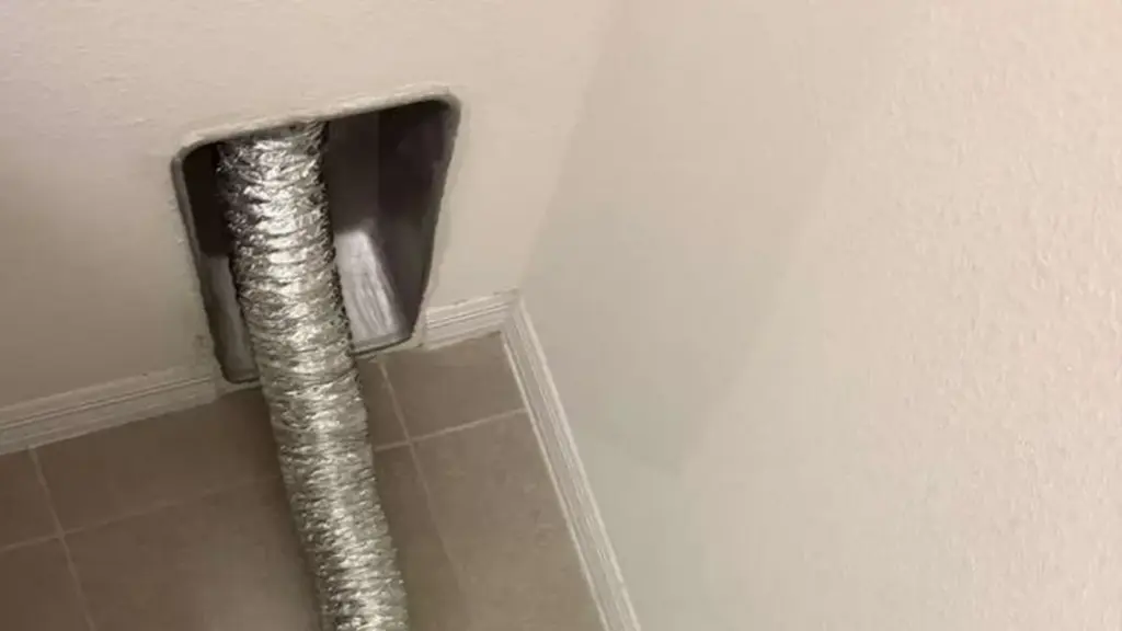 A licensed HVAC technician in a Tampa attic kneeling beside a section of deteriorating silver flex duct, holding a flash